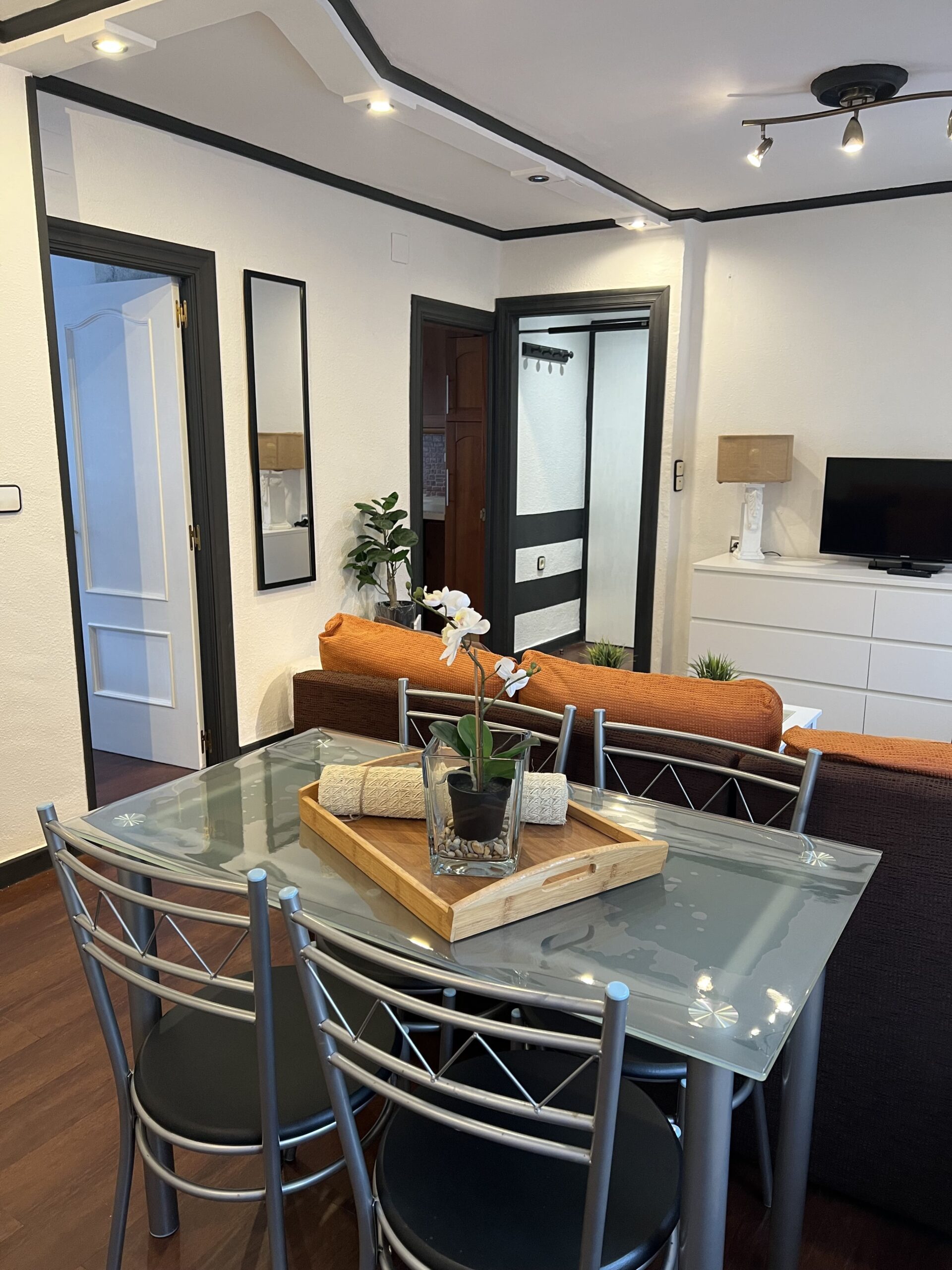 Después: Comedor con mesa de cristal y estanterías decoradas. Antes: comedor con paredes moradas.