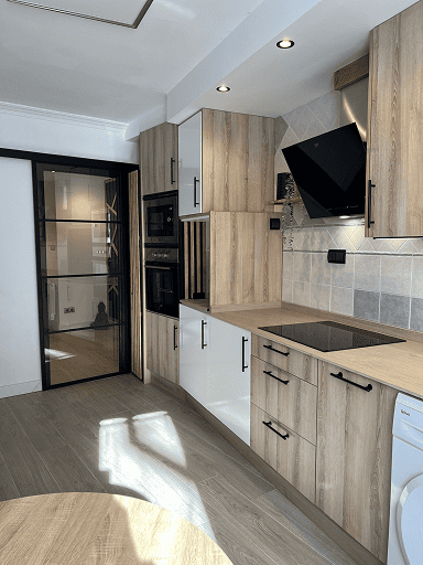 Cocina reformada con muebles de madera, campana negra y electrodomésticos integrados