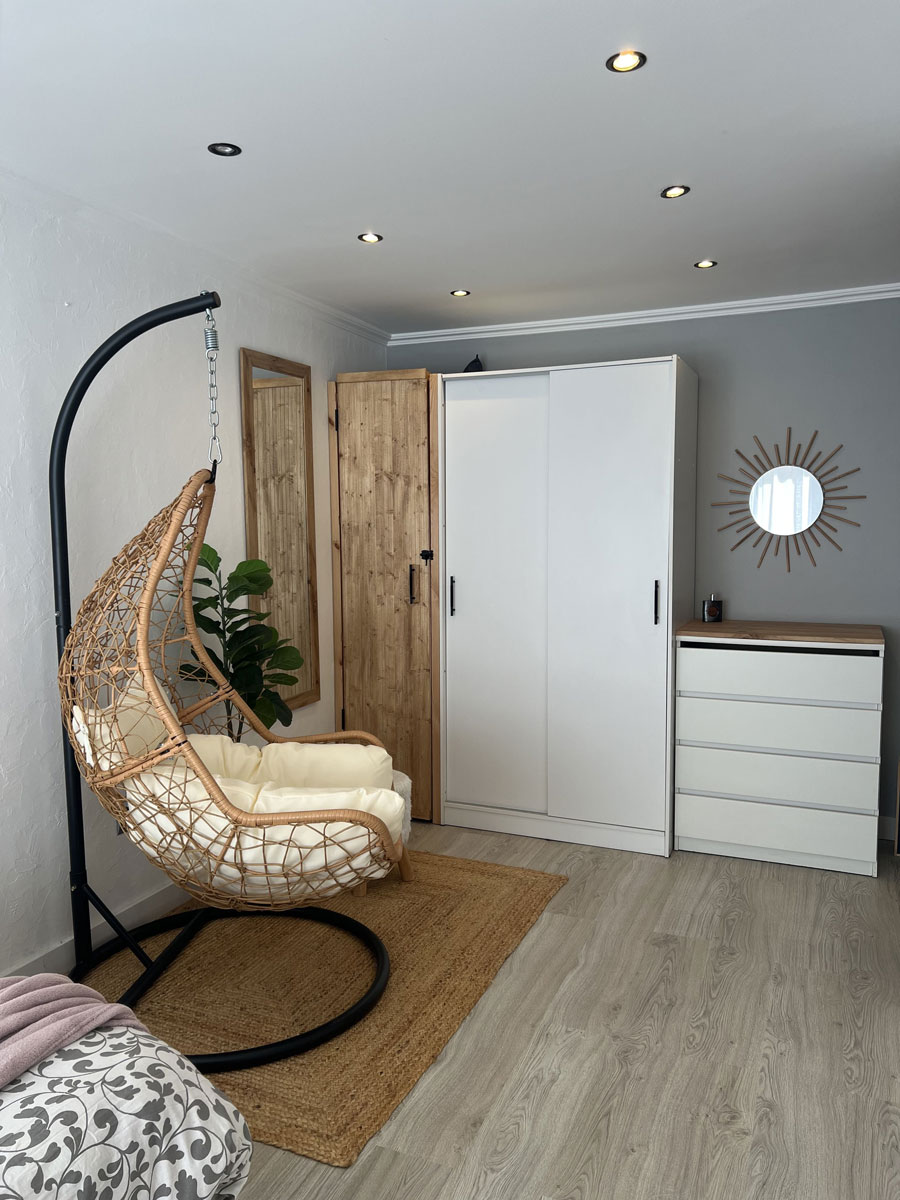 Después: Dormitorio con sillón colgante, armario blanco y cómoda. Antes: habitación en obra con escalera y armario.
