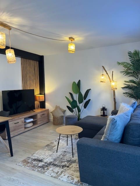 Después: Salón con sofá azul, mueble de TV y plantas. Antes: salón desordenado y sin decorar.