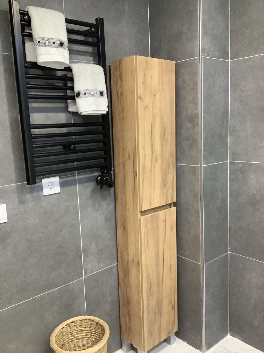 Después: Baño con toallero negro y revestimiento gris. Antes: baño antiguo con lavadora.