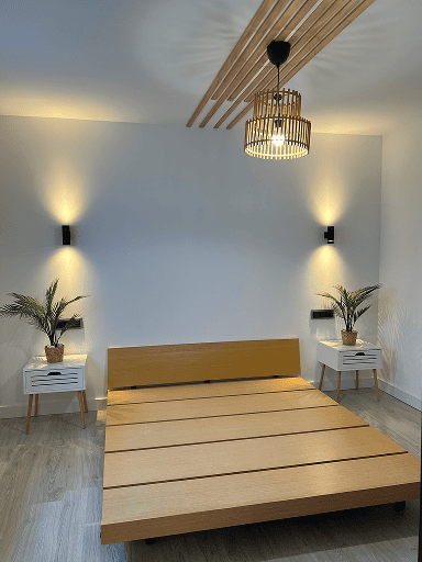 Dormitorio con cama de madera, lámpara de bambú y apliques de pared