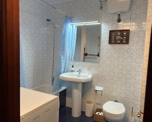 Antes de la reforma: baño antiguo con azulejos azules, bañera y cortina